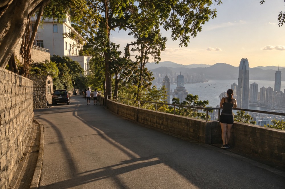 A flat paved walking path along Lugard Road with harbour views opening between trees