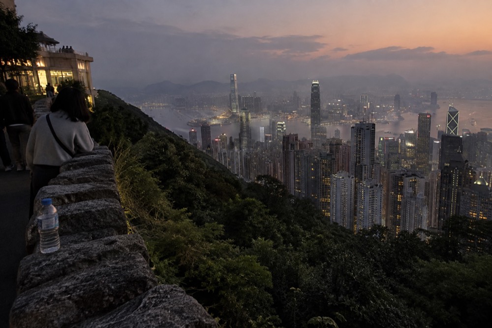 View over Hong Kong harbour skyline from the hilltop at dusk with lights beginning to show