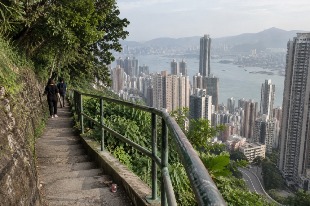 Terraced hillside path above Hong Kong towers with the harbour in the distance