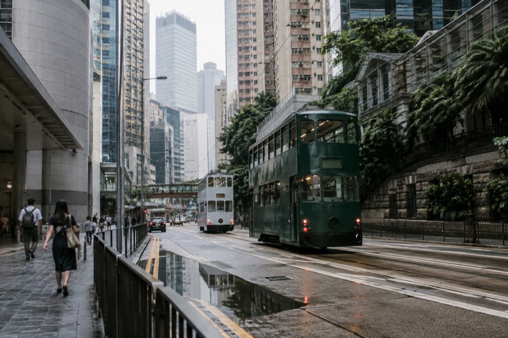 A narrow Hong Kong street with double-decker trams and tall residential buildings on both sides