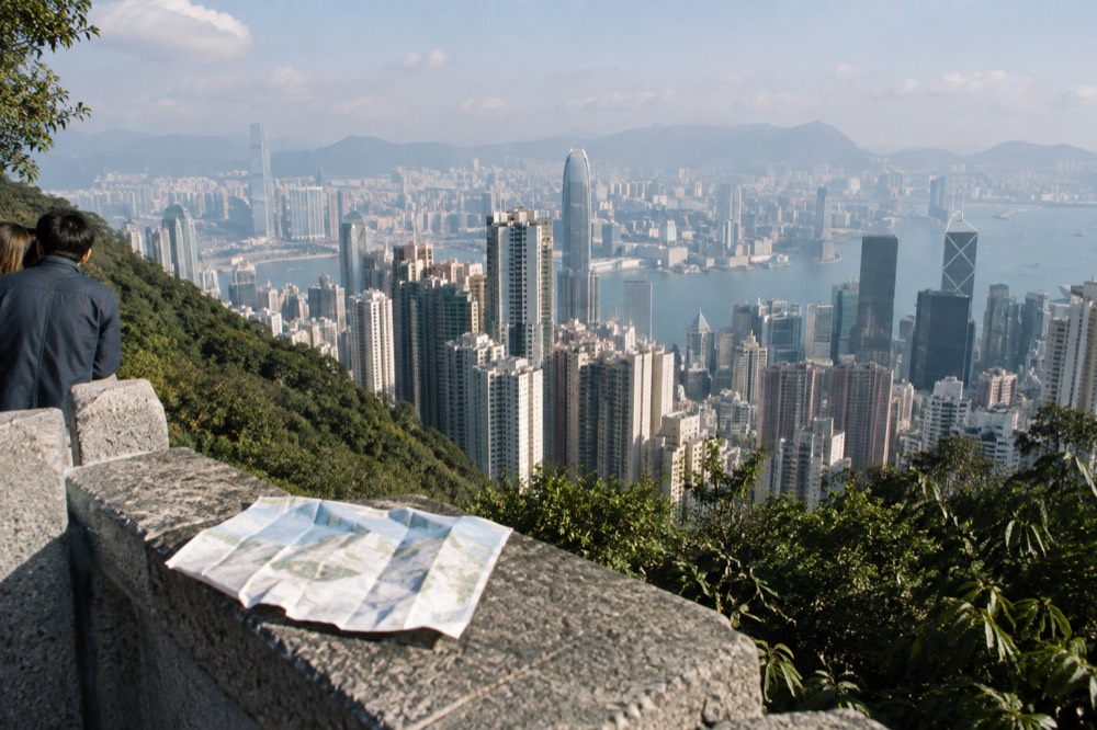 View from a high Peak viewpoint over Hong Kong skyline and harbour under clear afternoon sky