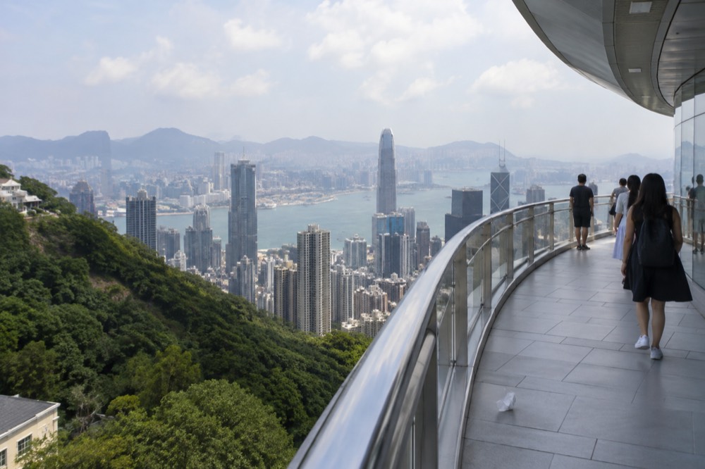 Rooftop observation deck railing overlooking dense Hong Kong skyscrapers and the harbour