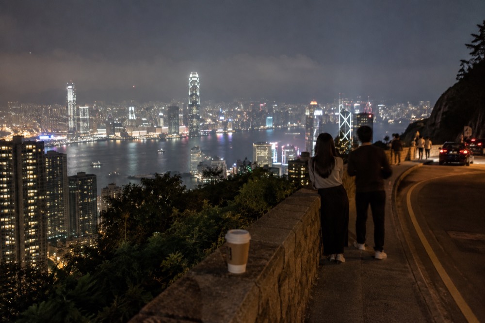 Lit towers of the Hong Kong skyline across Victoria Harbour seen from the Peak at night