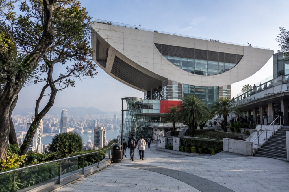 Modern wok-shaped building on a hilltop above city towers