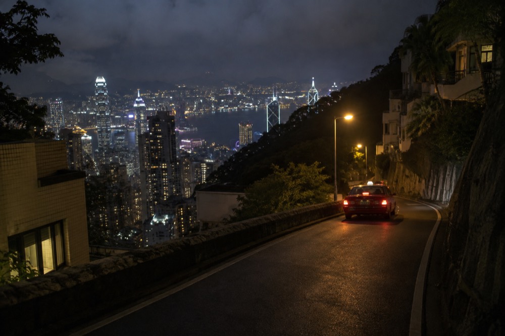 Night road descending a hillside with city lights below