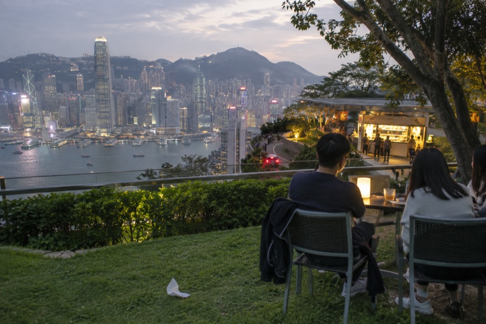 Diners at an outdoor table with the lit skyline across the water